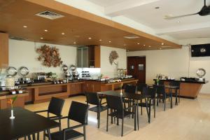a restaurant with tables and chairs and a kitchen at Zia Hotel Kuta in Kuta