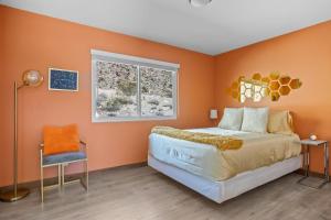 a bedroom with orange walls and a bed and a window at Neon Moon An Elevated Experience w Pool and Spa in Joshua Tree