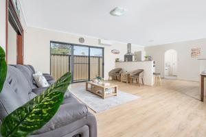 a living room with a couch and a table at Spacious 4BR House Right Near The Beach - Fast WIFI and Massive 85' TV in Geraldton