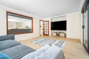 ein Wohnzimmer mit einem Sofa und einem Flachbild-TV in der Unterkunft Spacious 4BR House Right Near The Beach - Fast WIFI and Massive 85' TV in Geraldton