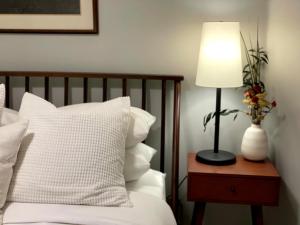 フィラデルフィアにある2BR in Heart of Queen Village - walk to everything!のベッドサイドのテーブルの上に灯り(白い枕付)