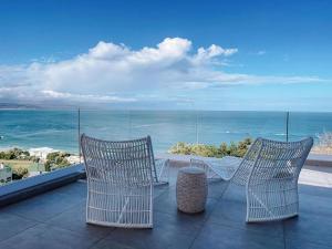dwa krzesła i stół na balkonie z widokiem na ocean w obiekcie Dizzy Hill Villa with 270° Breathtaking Views. Pool + Patio w mieście Plettenberg Bay