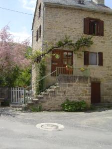 a stone house with a staircase and a door at La Maison de Juliette in Les Salelles