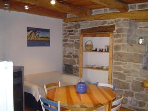 a dining room with a table and a stone wall at La Maison de Juliette in Les Salelles