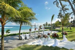 una ceremonia de boda en la playa con sillas blancas y flores en Candi Beach Resort & Spa, en Candidasa
