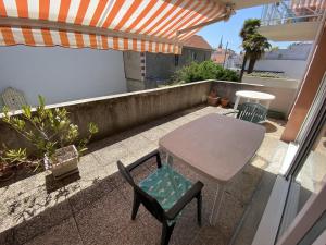 einen Tisch und Stühle auf einem Balkon mit Sonnenschirm in der Unterkunft Appartement Arcachon, 2 pièces, 3 personnes - FR-1-474-167 in Arcachon