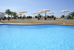 Hotel Nerja Club Spa by Dorobe في نيرخا: مسبح ازرق كبير مع كراسي ومظلات