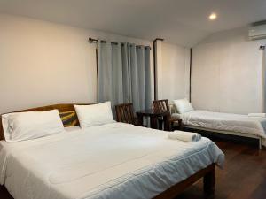 1 dormitorio con 2 camas, mesa y sillas en บ้านระการีสอร์ต (Banraka Resort), en Ban Tha Chang