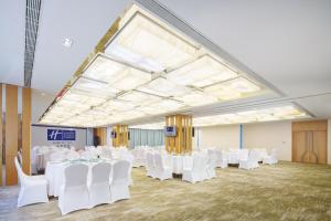 um quarto amplo com mesas brancas e cadeiras brancas em Holiday Inn Express City Centre Dalian, an IHG Hotel em Dalian