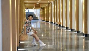 a young man sitting on a bench in a hallway at FLC City Hotel Beach Quy Nhon in Quy Nhon