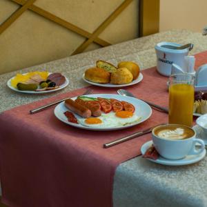 a table with plates of breakfast foods and a cup of coffee at Jumbaktas Astana Hotel in Astana