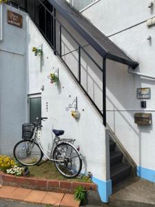 uma bicicleta estacionada ao lado de um edifício com escadas em Casa del girasolカサデルヒラソル em Moriguchi