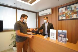 two men wearing masks standing at a reception counter at Saltstayz Grand Sky - Unitech Cyber Park in Gurgaon