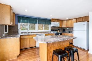 a kitchen with wooden cabinets and a white refrigerator at Hot Tub, Wraparound Deck, & WiFi at Chalet Cabin in Inwood +21 photos