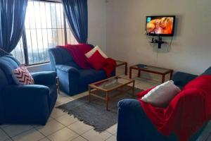 a living room with two blue chairs and a tv at Villa Del Sol Unit 8 in Margate