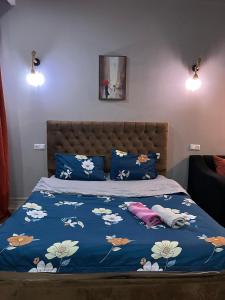 a bed with a blue comforter with flowers on it at Avlabari Apartaments Nia in Tbilisi City