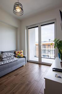 een woonkamer met een bank en grote ramen bij ENERGYLANDIA Zator Apartament Krzyś in Zator