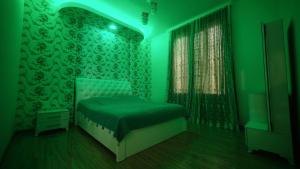 Dormitorio verde con cama y ventana en Guesthouse - Family Hotel en Bagdatʼi