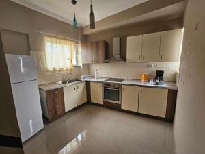 eine Küche mit weißen Schränken und einem weißen Kühlschrank in der Unterkunft Christa's Home near ATH Airport in Markopoulo