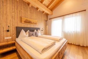 1 Schlafzimmer mit 2 Betten an einer Holzwand in der Unterkunft Reidenhof in Sexten