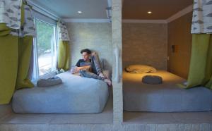 mężczyzna siedzący na dwóch łóżkach w pokoju w obiekcie La Zona Hostel w mieście San Salvador