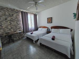 a bedroom with two beds and a brick wall at La Zona Hostel in San Salvador