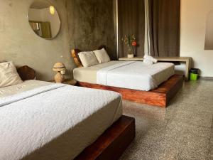 two beds in a hotel room with a mirror at La Zona Hostel in San Salvador