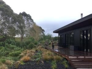 a house with a deck next to a field at Whakaipo Bay Cabin Retreat Taupo in Taupo
