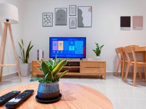 a living room with a tv and a table with a plant at THE SHORE SEAVIEW Centre Of The City in Kota Kinabalu