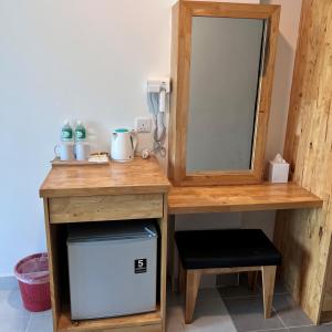 a wooden desk with a mirror and a small refrigerator at Langkapuri Resort Langkawi in Pantai Cenang