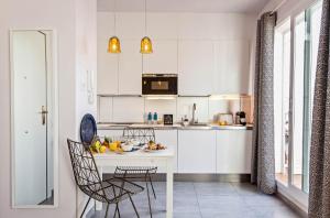 バルセロナにあるSweet Inn - Atic Graciaの白いキャビネット、テーブルと椅子付きのキッチンが備わります。