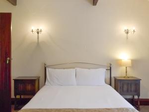 1 dormitorio con 1 cama blanca y 2 mesitas de noche en The Threshing Barn- 25347, en Findern