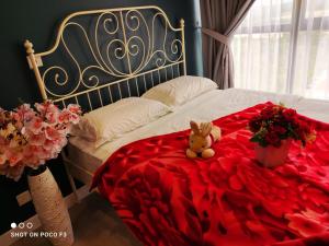 un ours en peluche assis sur un lit recouvert de roses dans l'établissement Cozy Studio unit,Cyberjaya,Wifi, Netflix,Free parking, à Cyberjaya