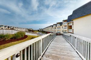 un paseo marítimo de madera que conduce a un balcón de apartamentos en condominio en A Place At The Beach III en Atlantic Beach