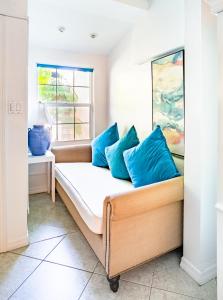 a couch with blue pillows in a room with a window at Beach Living at Island Pine Villas (BLV) in George Town