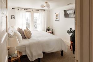 Un dormitorio blanco con una gran cama blanca y una ventana en The Bentley Inn, en Bay Head