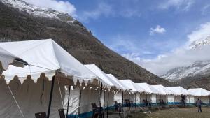 une rangée de tentes blanches devant une montagne dans l'établissement Bhrigu Camps, à Jispa
