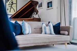 een bank met blauwe en witte kussens en een piano bij Host & Stay - The Musician's Apartment with Grand Piano in Liverpool