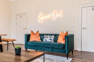 eine grüne Couch in einem Wohnzimmer mit Neonschild in der Unterkunft Host & Stay - The Rodney Townhouse in Liverpool