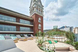 un bâtiment avec une tour d'horloge et des chaises longues dans l'établissement ROYAL CHESTER NAGASAKI hotel&retreat, à Nagasaki