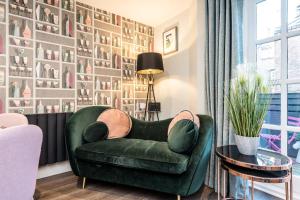 una silla verde en una sala de estar con una pared de cuadros en Host & Stay - The Pilgrim Coach Houses, en Liverpool