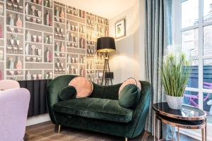 a green chair in a living room with a wall of pictures at Host & Stay - The Pilgrim Coach Houses in Liverpool