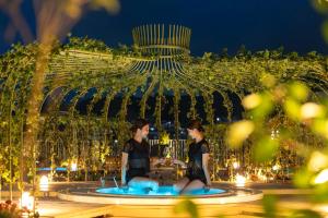 two women sitting in a fountain at night at ROYAL CHESTER NAGASAKI hotel&retreat in Nagasaki