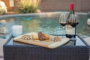 a table with a tray of food and two glasses of wine at Desert Oasis Amazing Pool Waterfall Firepit Office in Casa Grande