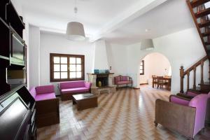 a living room with purple chairs and a tv at Wonderful villa with huge yard, at Potamos beach in Epanomi