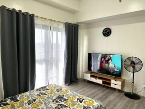 a bedroom with a bed and a flat screen tv at Minimalist studio unit in Davao City