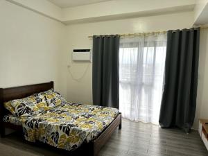 a bedroom with a bed and a window with curtains at Minimalist studio unit in Davao City