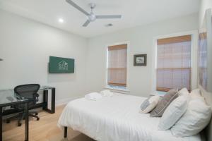 a bedroom with a white bed with a desk and windows at Twin Palms Beach Old Village 5-Min to Dwntwn in Charleston