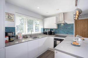una cocina con armarios blancos y azulejos azules en Kentmere Haven - 2 Bedroom - Cycle Storage, en Kendal