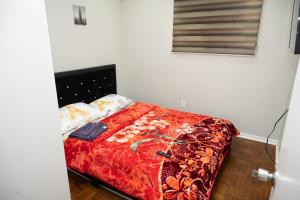 a bedroom with a bed with a red blanket at Nathan’s Place in Brampton